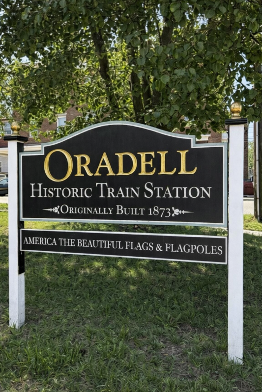 Historic Oradell Station Sign Featuring America The Beautiful Flags & Flagpoles Historic oradell station america the beautiful flags flagpoles